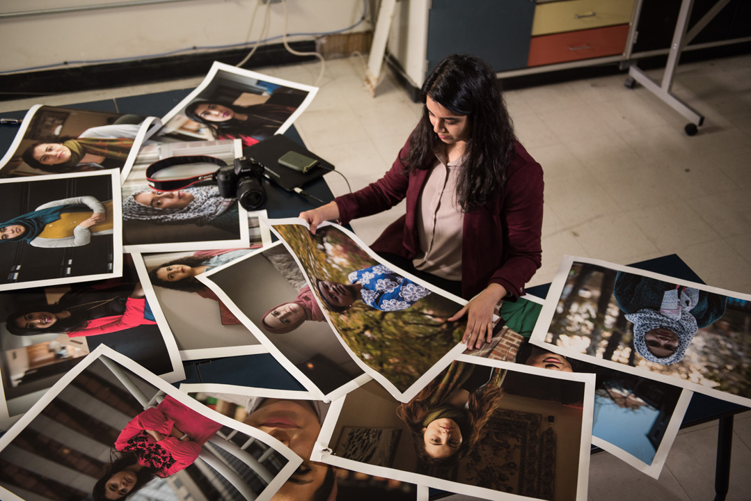 A student reviews photos spread out on a table in a classroom