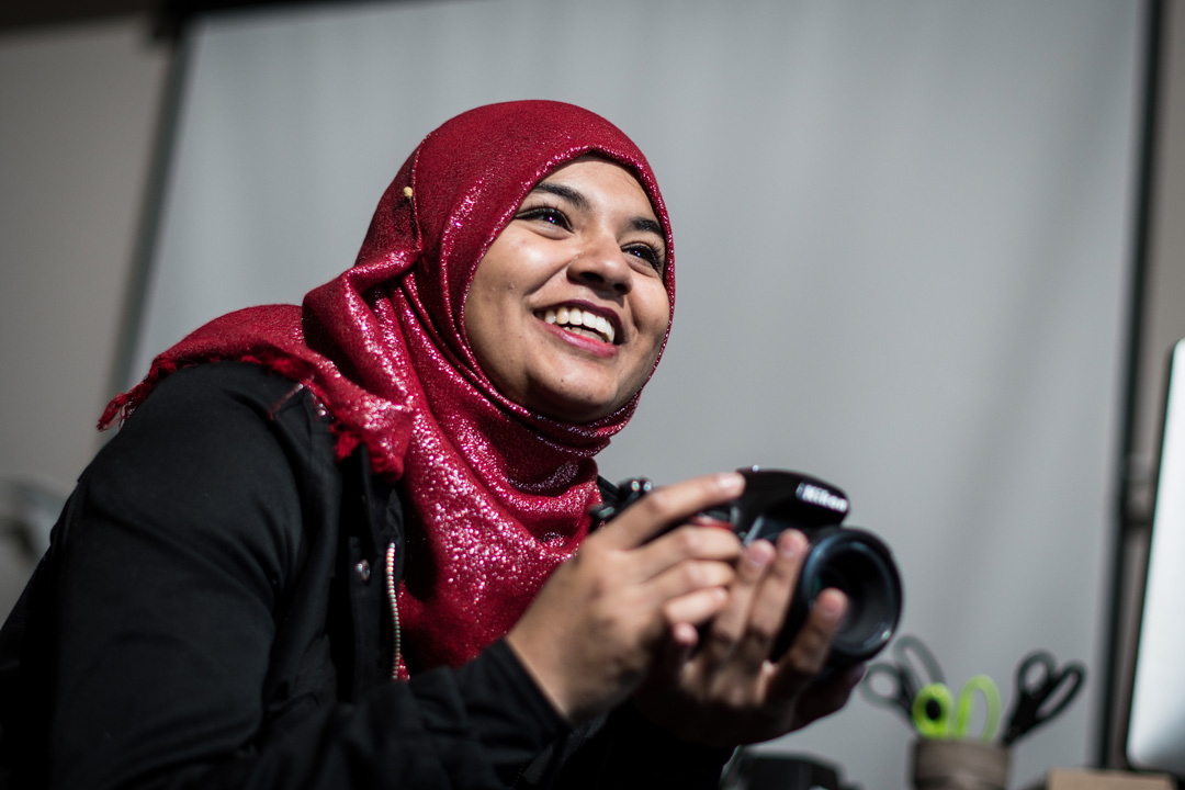 A Corcoran student, holding a camera, smiles after taking a photo