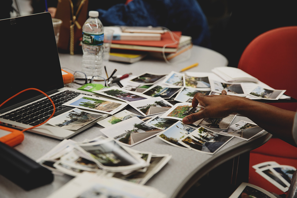 Corcoran student works with photography prints at a laptop