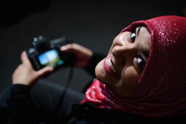 A Corcoran alumnus looks at the camera while holding her camera